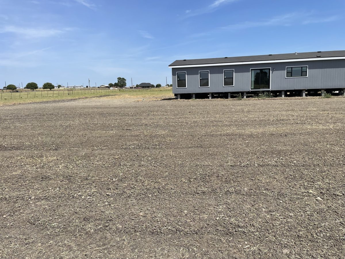 Cleared and leveled land next to a home, ready for landscaping