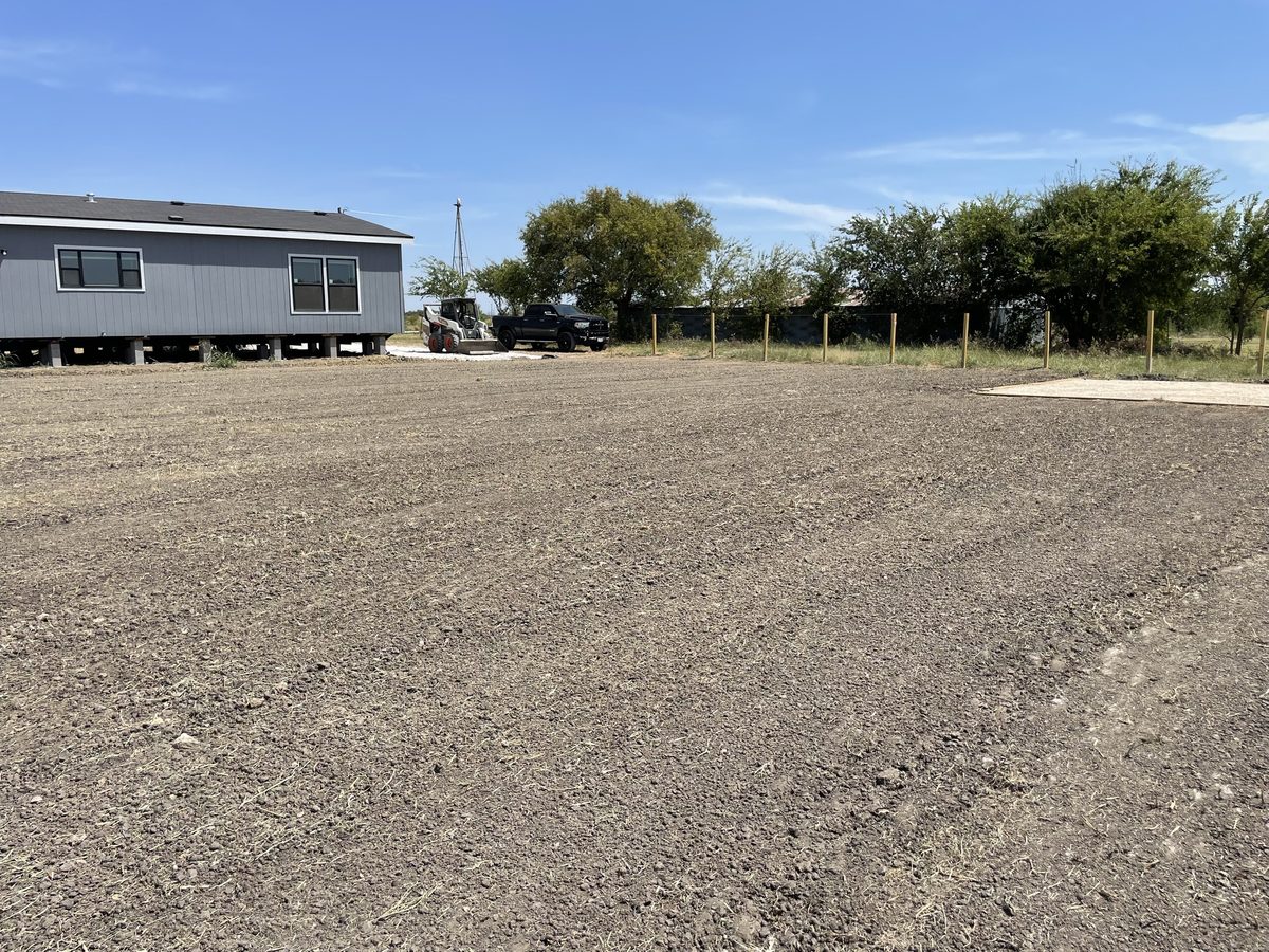 Freshly graded lot beside a manufactured home in North Texas
